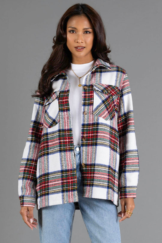 A woman models the Panache Apparel Collection Ivory & Multicolored Plaid Jacket, styled with a white turtleneck and blue jeans, standing against a plain gray background.