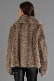 A person with long dark hair is shown from the back, wearing the Panache Apparel Collection Two Tone Faux Fur Jacket and black leather pants against a plain gray background.