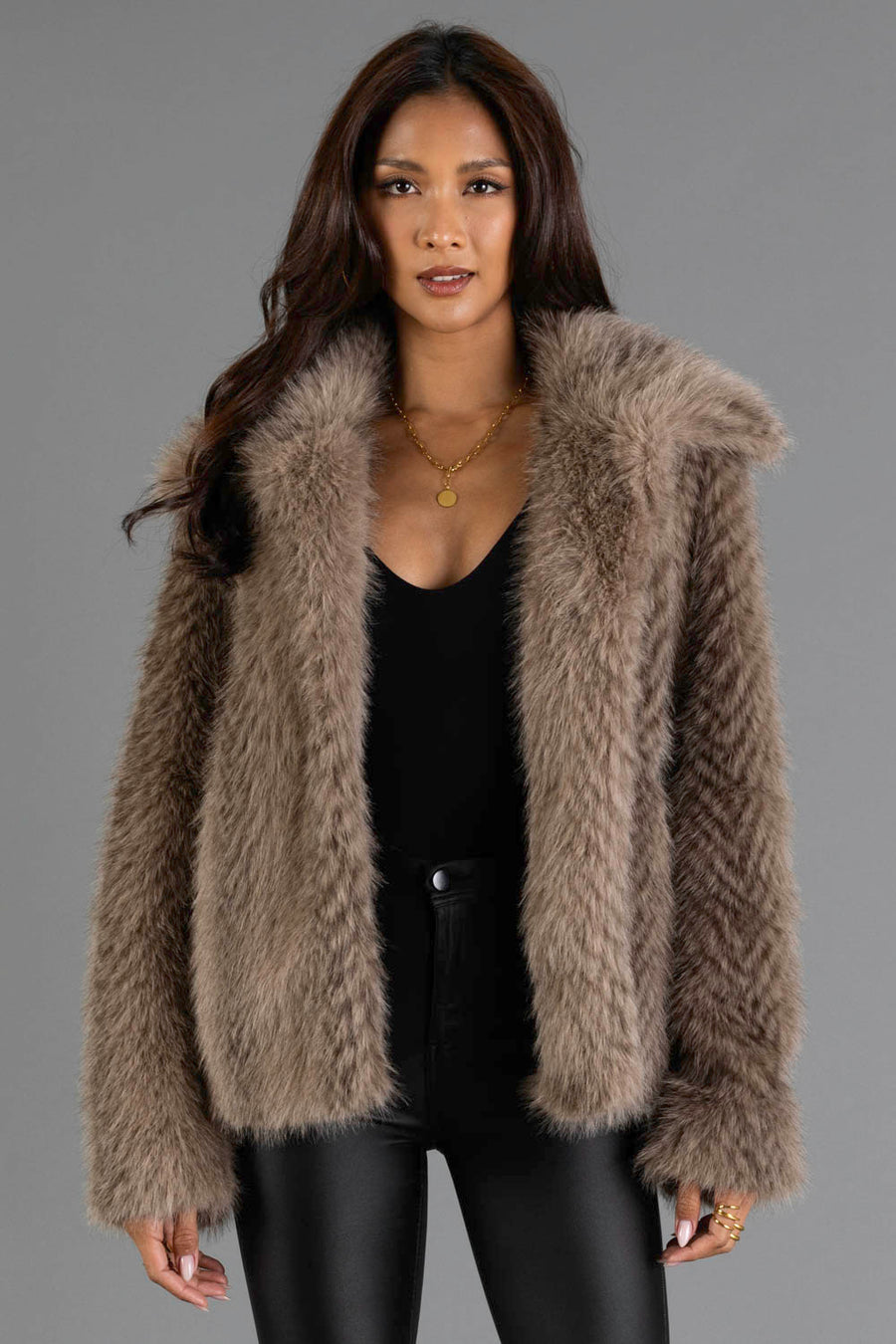 Model is wearing the Two Tone Faux Fur Jacket from Panache Apparel Collection over a black top and black pants, standing against a gray background.