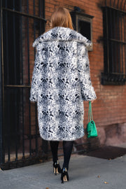 A person seen from behind wearing an oversized Leopard Faux Fur Maxi Coat from Panache Apparel Collection, black tights, black heels, and carrying a small green chain-strap handbag.