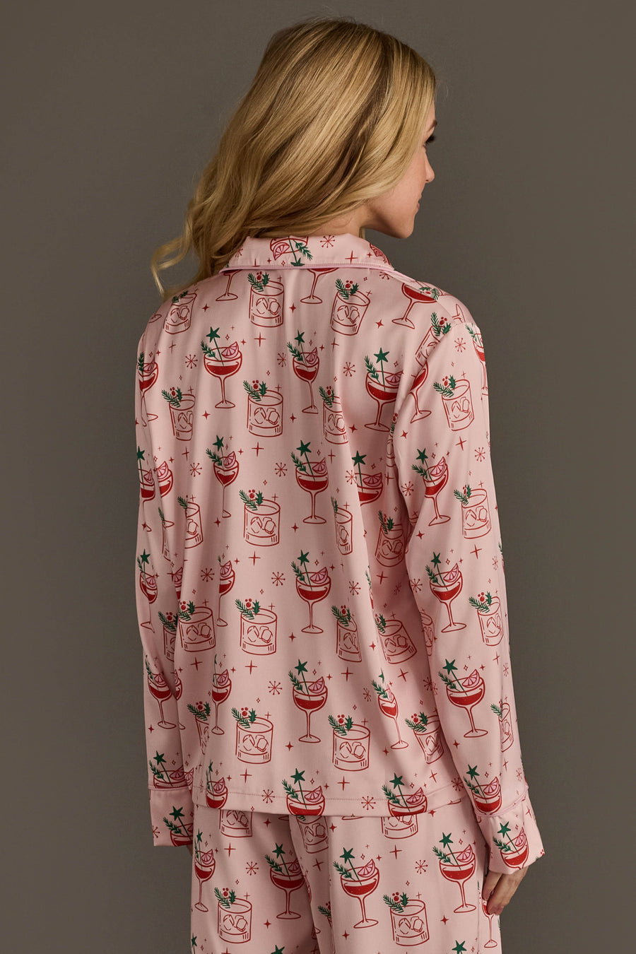 Back view of a person wearing a Light Pink Christmas Cocktails Satin Pajama Set featuring a light pink satin fabric printed with a pattern of Christmas cocktails.