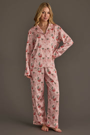 A person wearing a Light Pink Christmas Cocktails Satin Pajama Set in light pink, featuring a repeating print of cocktail glasses decorated with festive elements.