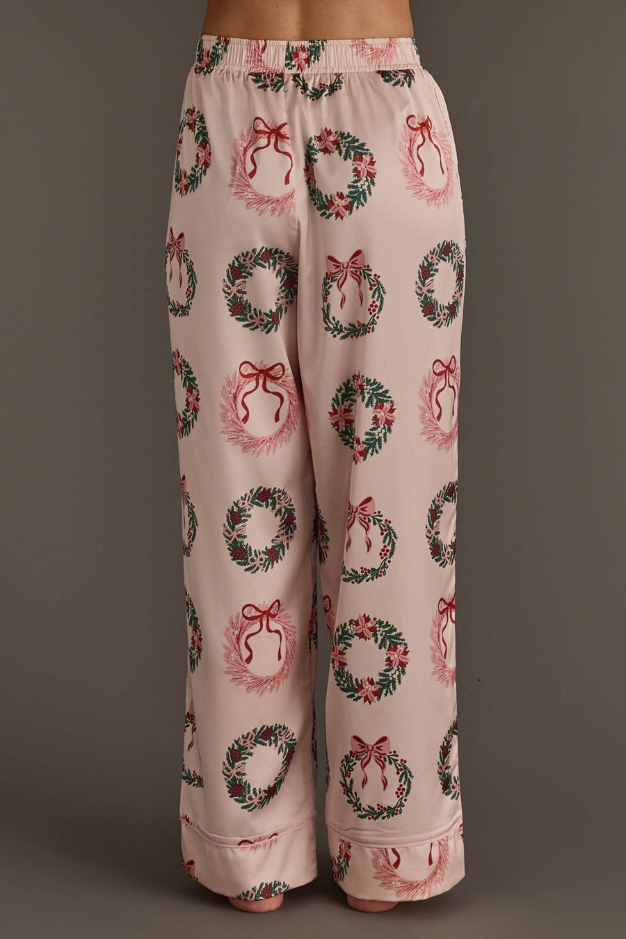 Light pink satin pajama pants from the Christmas Wreaths Satin Pajama Set featuring an all-over print of Christmas wreaths with red bows.