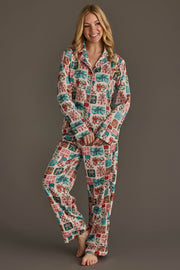 A person wearing a Panache Apparel Collection Christmas Presents Satin Pajama Set, featuring a pink long-sleeved button-down top and matching pants with a colorful Christmas present print.