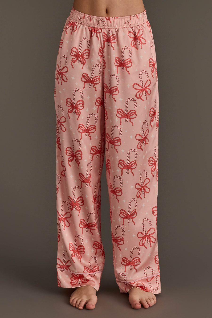 Light pink Candy Canes & Bows Satin Pajama Set pants featuring a repeating holiday loungewear pattern of red candy canes and bows.