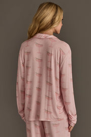 A person seen from behind wearing a light pink Christmas Cocktails Jersey Pajama Set featuring a repeating cocktail glass pattern.