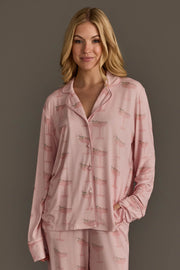 Woman wearing the light pink long-sleeved button-up top from a Christmas Cocktails Jersey Pajama Set featuring a festive cocktail print.