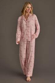A woman wearing a light pink Christmas Cocktails Jersey Pajama Set featuring a repeating cocktail glass print.