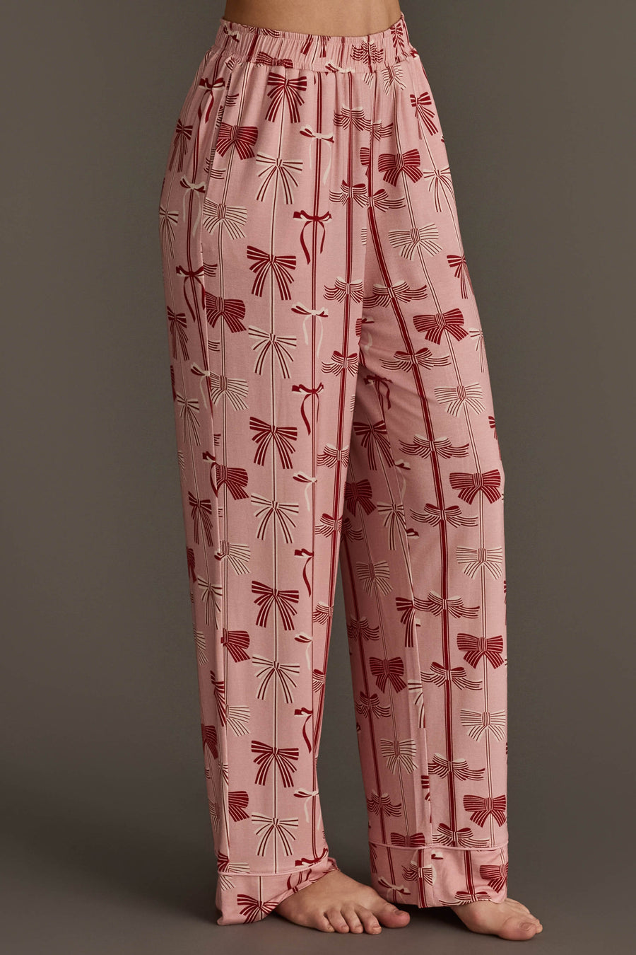 Light pink Bows Jersey Pajama Set pants in a jersey fabric featuring an all-over festive bow print with red and white bows and vertical lines.