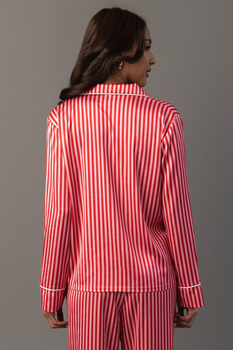 A person wearing a Panache Apparel Collection Red & Pink Striped Satin Pajama Set featuring a red and pink vertical stripe pattern.