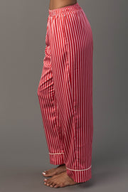Side view of a person wearing Red & Pink Striped Satin Pajama Set pants in red and pink with white piping at the cuffs.
