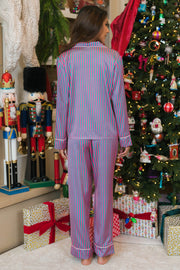 A person stands with their back to the camera wearing a Pink & Green Striped Satin Pajama Set featuring vertical pink and green buttons and white trim.