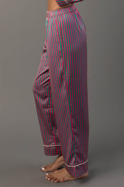A person wearing pink and green striped pajama pants from the Pink & Green Striped Satin Pajama Set, featuring white piped trim at the cuffs.