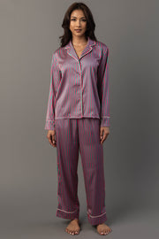 A person wearing a Pink & Green Striped Satin Pajama Set consisting of a long-sleeved button-up shirt and matching pants in pink and green vertical stripes with white piping.