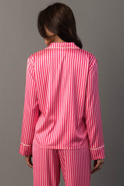 A person wears the Bright Pink & Light Pink Striped Satin Pajama Set, consisting of long-sleeved pajamas with a pattern of bright and light pink vertical stripes.