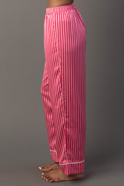 Profile view of Bright Pink & Light Pink Striped Satin Pajama Set pants featuring vertical bright and light pink stripes, an elastic waistband, and white trim at the cuffs.