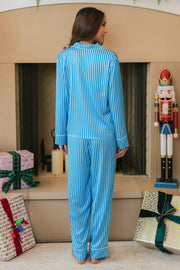 A person seen from behind wearing a Blue & Light Blue Striped Satin Pajama Set, consisting of a long-sleeved shirt and matching pants.