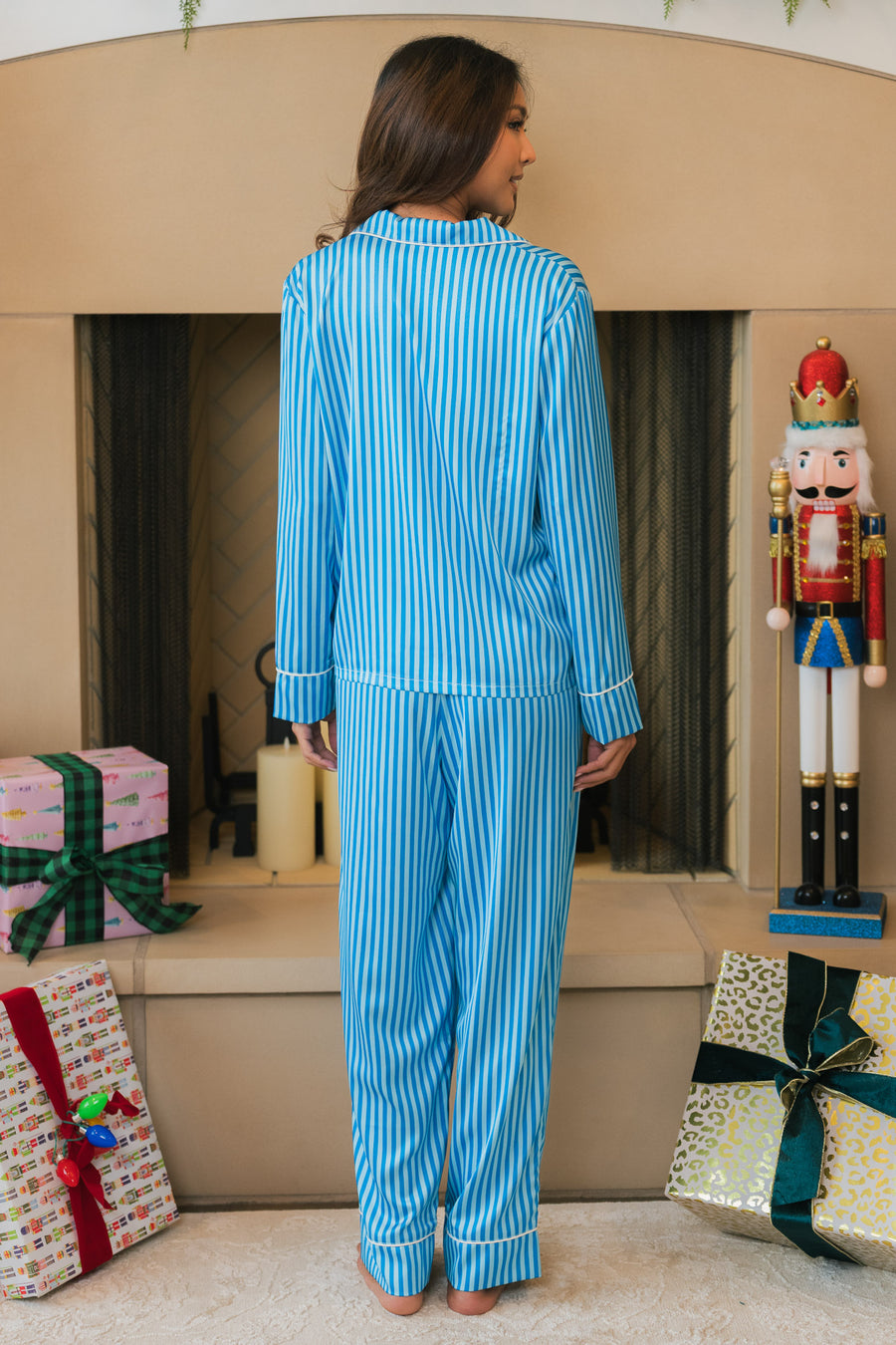 A person seen from behind wearing a Blue & Light Blue Striped Satin Pajama Set, consisting of a long-sleeved shirt and matching pants.