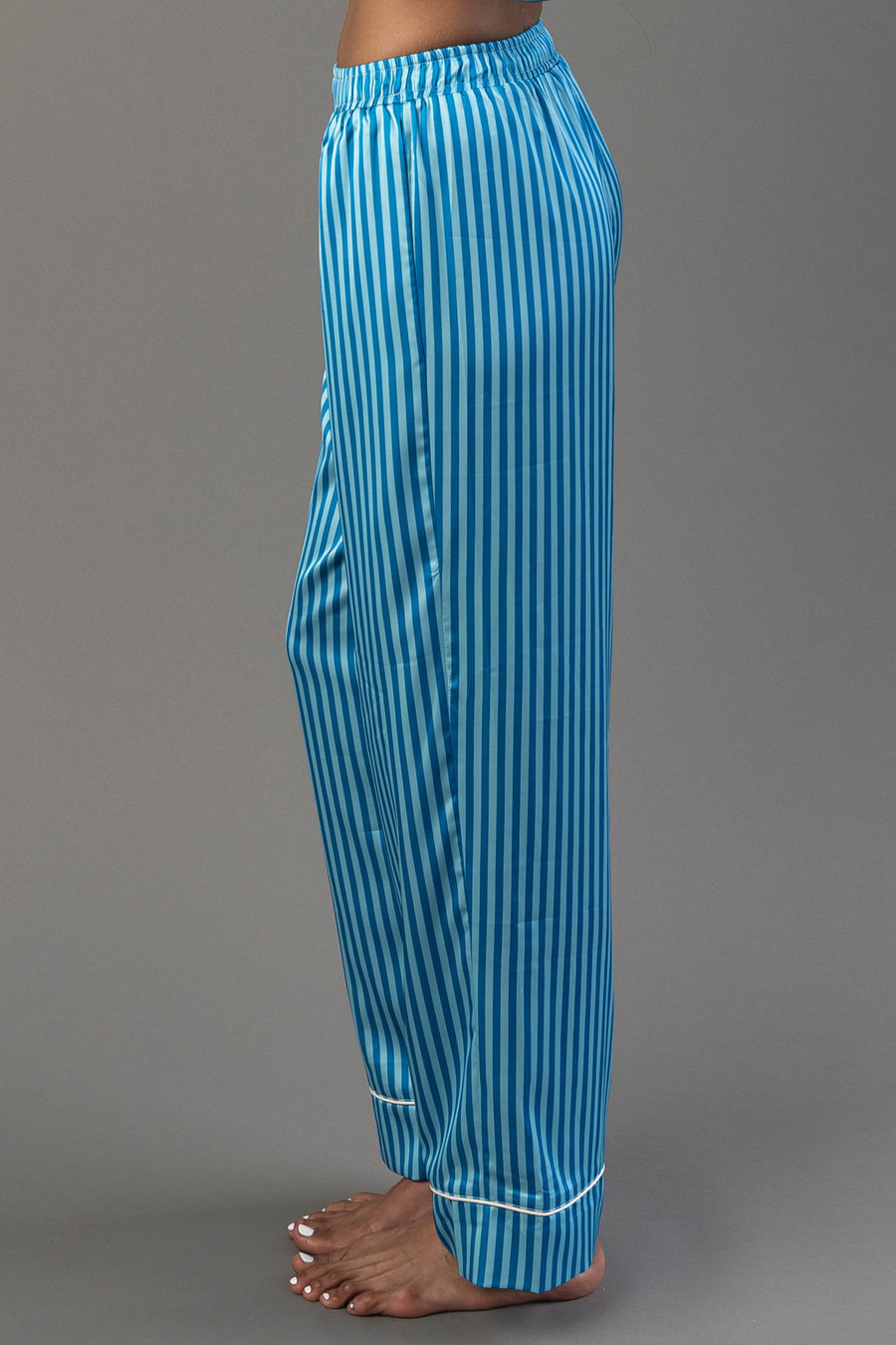 Side view of Blue & Light Blue Striped Satin Pajama Set pants, featuring blue and light blue stripes, a drawstring waist, and white piped cuffs.