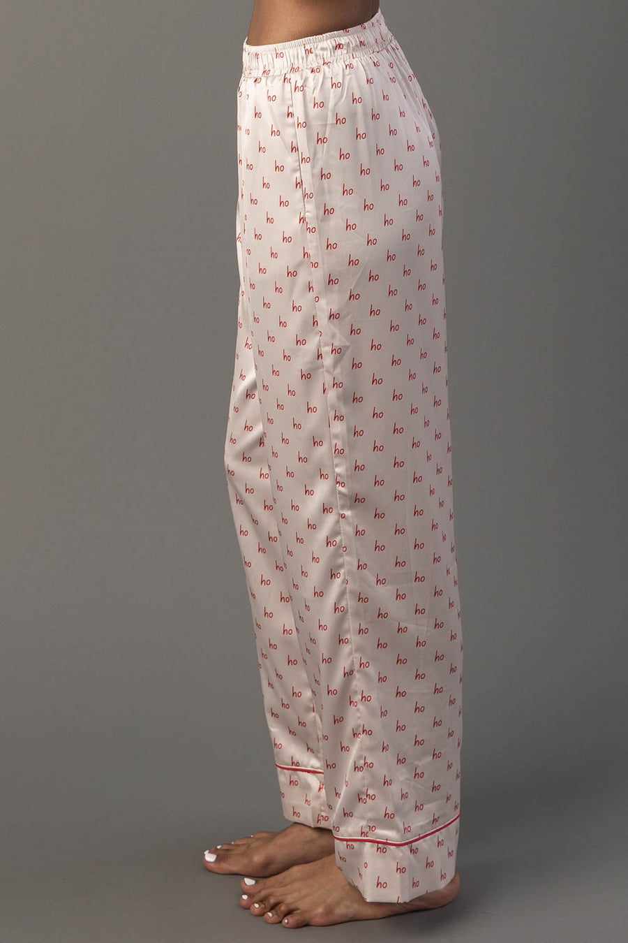 Ivory & Red Ho Ho Ho Satin Pajama Set pants in light-colored satin, patterned with small red ho text and finished with a red hem.
