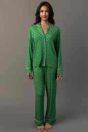 A person wearing a Green & Light Pink Ho Ho Ho Jersey Pajama Set, consisting of a green long-sleeved button-down top with a repeating ho ho ho print and light pink trim.