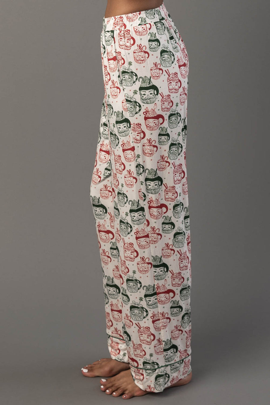 Side view of Ivory Santa Mugs Jersey Pajama Set pants featuring an all-over Santa mugs print in red and green.