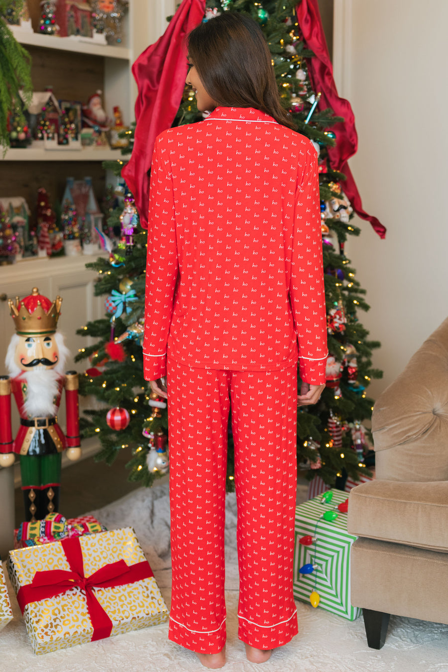 A person seen from behind wearing a Red & White Ho Ho Ho Jersey Pajama Set with a red holiday pattern featuring small white ho ho ho text.