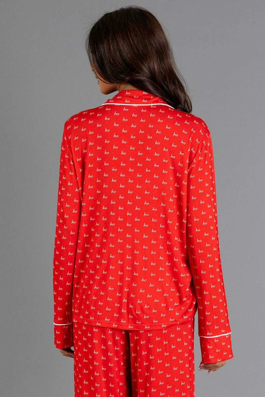 A person wearing a Red & White Ho Ho Ho Jersey Pajama Set featuring a repeating white print and white piping.