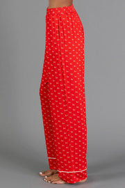 Side view of Red & White Ho Ho Ho Jersey Pajama Set pants in red with a repeating white ho ho ho print and white hem piping.