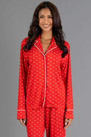A woman wears a red and white Ho Ho Ho Jersey Pajama Set featuring a notched collar, white piping, and a long-sleeve top with a white print.