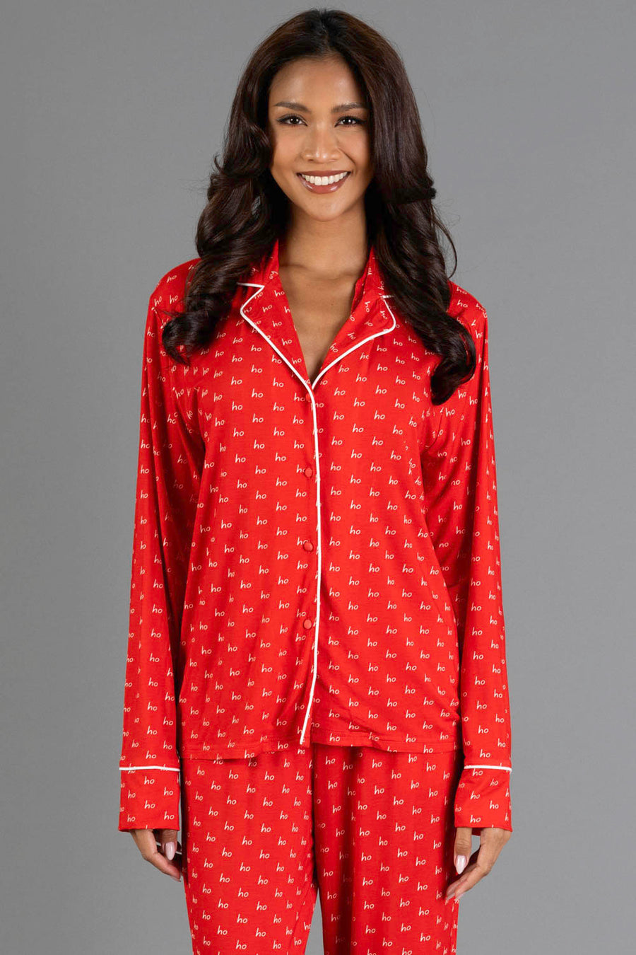 A woman wears a red and white Ho Ho Ho Jersey Pajama Set featuring a notched collar, white piping, and a long-sleeve top with a white print.