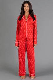 A woman wearing a Red & White Ho Ho Ho Jersey Pajama Set featuring a red jersey fabric with a white ho ho ho print and white piping trim.