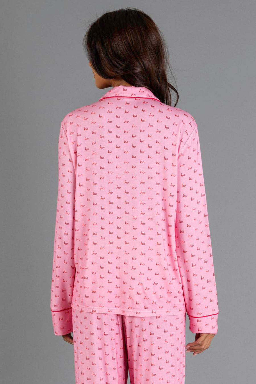Back view of a person wearing a Light Pink & Red Ho Ho Ho Jersey Pajama Set with a repeating red ho ho ho print and red piping.