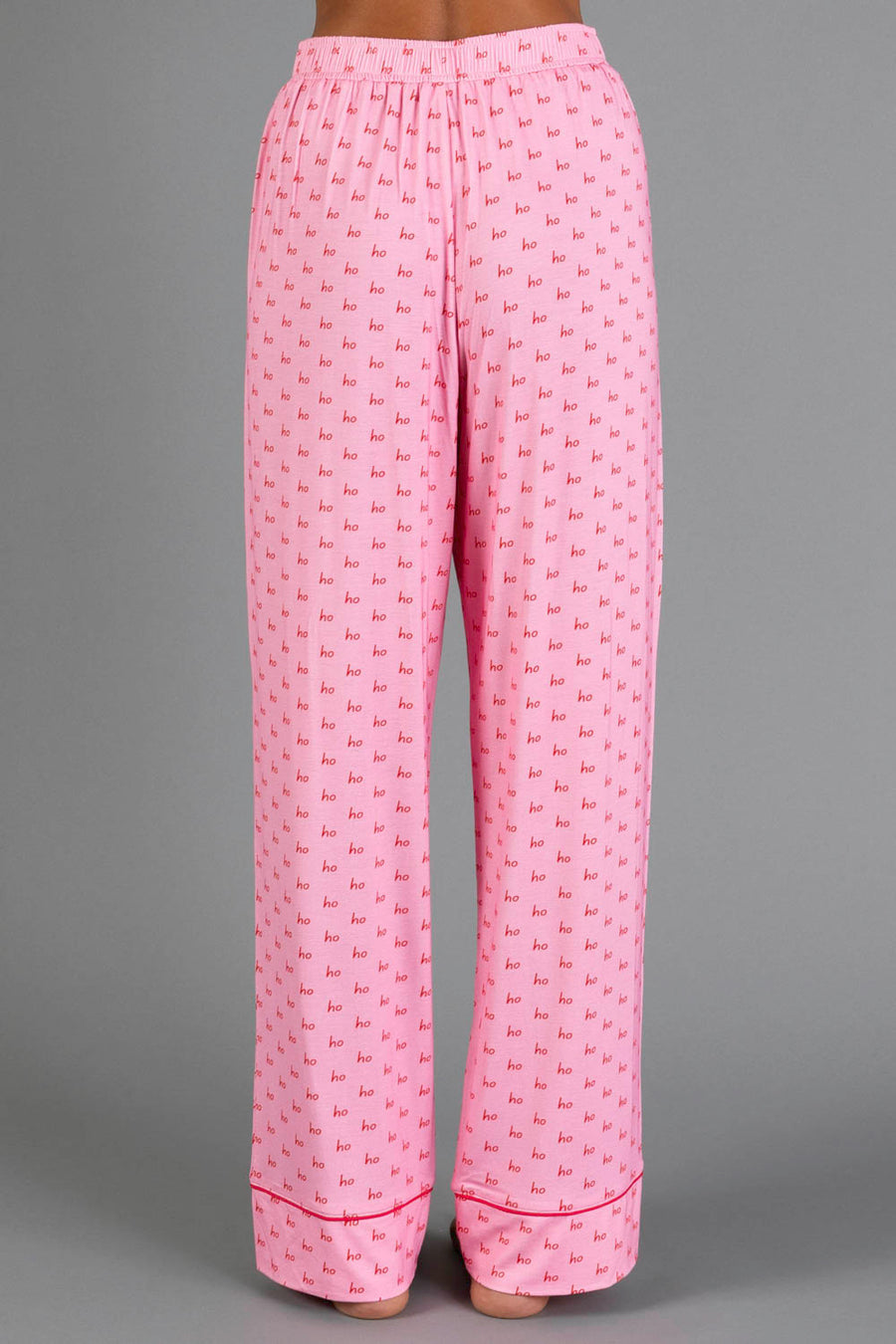 Light Pink & Red Ho Ho Ho Jersey Pajama Set featuring light pink holiday pajama pants with an all-over print of the words ho ho ho in red text.