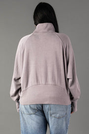 A person with long dark hair is seen from the back, wearing a Panache Apparel Collection Gray Quarter Zip Sweatshirt and light blue jeans against a plain gray background.