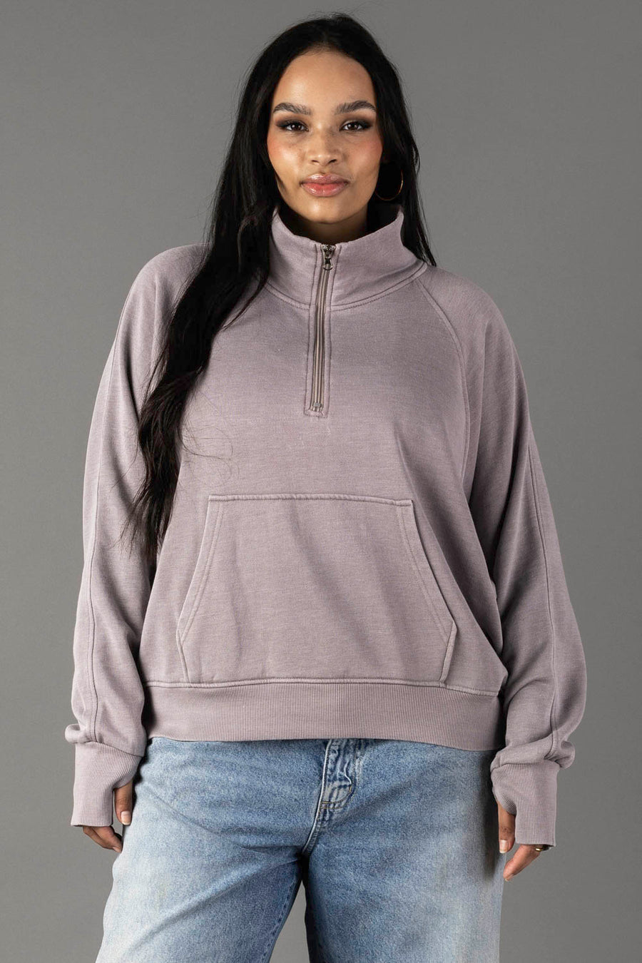 A woman with long dark hair wears the Panache Apparel Collection Gray Quarter Zip Sweatshirt and blue jeans, standing against a plain gray background.