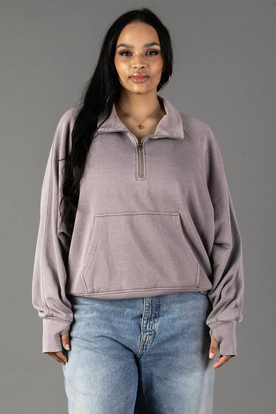A woman with long dark hair wears the Panache Apparel Collection Gray Quarter Zip Sweatshirt with light blue jeans, standing against a plain gray background.