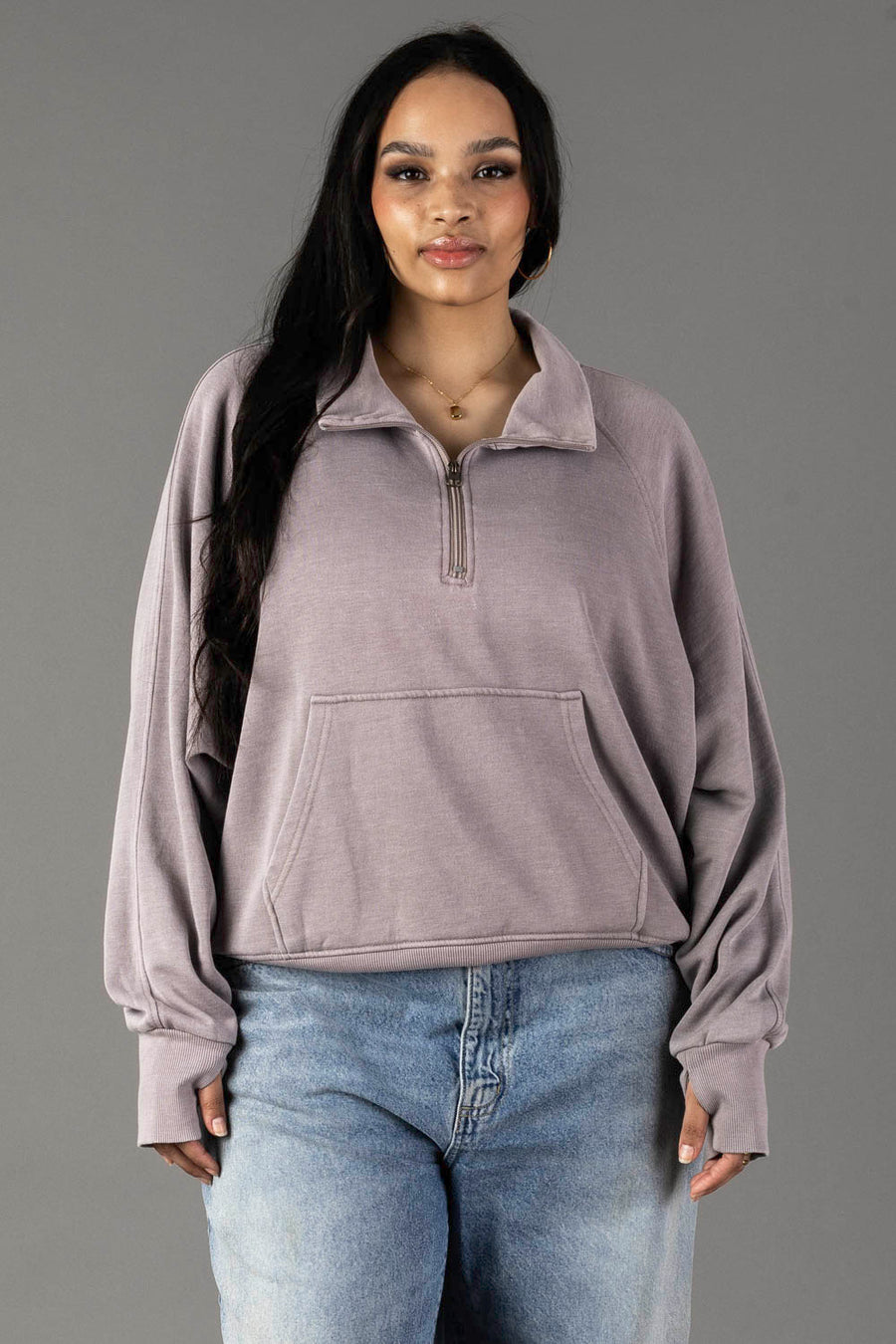 A woman with long dark hair wears the Panache Apparel Collection Gray Quarter Zip Sweatshirt with light blue jeans, standing against a plain gray background.