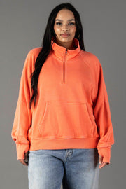 A woman in the Panache Apparel Collection Coral Quarter Zip Sweatshirt, styled with light blue jeans, stands against a plain gray background.