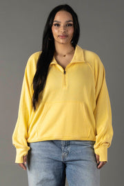 A woman with long dark hair models the Panache Apparel Collection Yellow Quarter Zip Sweatshirt with light blue jeans, standing against a plain gray background and facing the camera with a neutral expression.