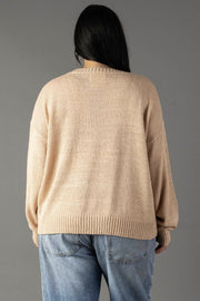 A person with long dark hair is seen from behind, wearing the Panache Apparel Collection’s Tan & Ivory Coffee Weather Lightweight Sweater and light blue jeans, standing against a plain gray background.