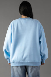 A person with long dark hair, shown from the back against a plain gray background, wears a light blue Panache Apparel Collection Lazy Lake Day Sweatshirt paired with blue jeans.