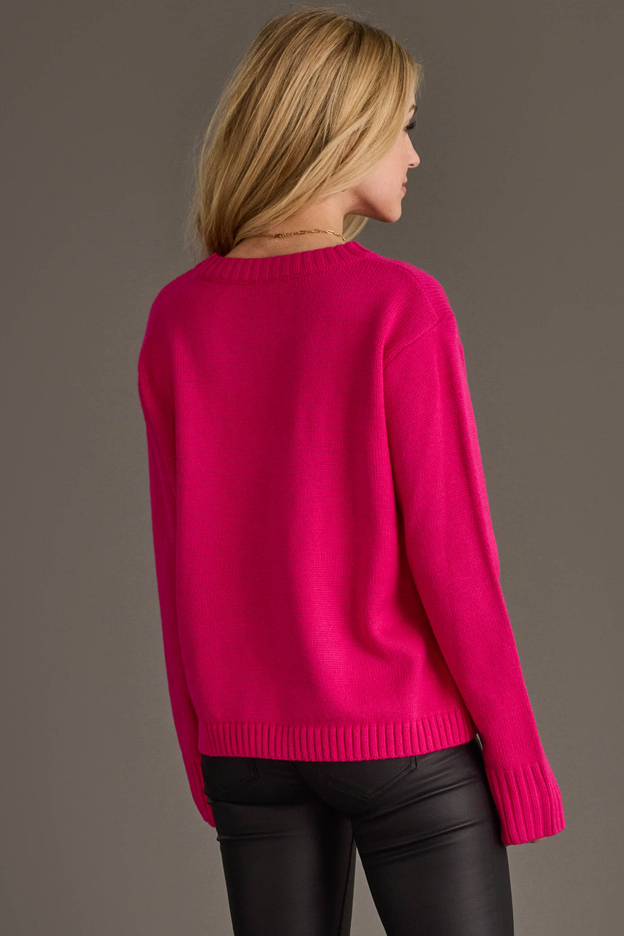 A woman seen from behind wearing the Pink & Light Pink Merry Sweater, a relaxed fit pink knit crewneck with ribbed cuffs and hem.