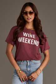 A woman wearing a burgundy Wine Weekend Tee with the words printed in white letters.