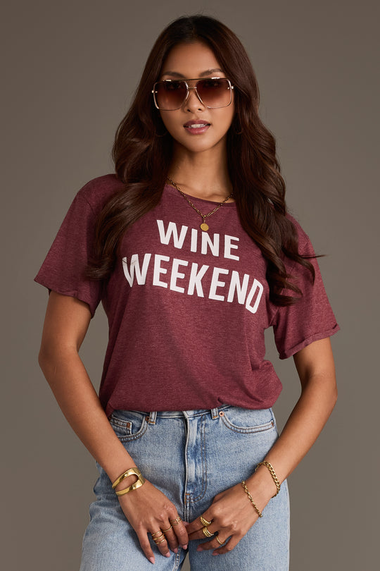 A woman wearing a burgundy Wine Weekend Tee with the words printed in white letters.