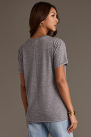 A woman seen from behind, wearing a relaxed fit gray Panache Apparel Collection Gray Wine Season Tee with a vertical seam down the center of the back, paired with light-wash jeans.