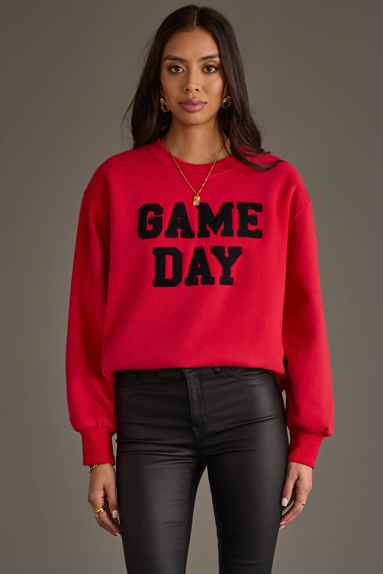 A woman stands facing forward against a plain gray background, wearing the Panache Apparel Collection Red & Black Game Day Sweatshirt paired with black pants.