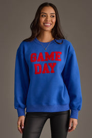 A woman stands smiling against a plain gray background, wearing the Panache Apparel Collection's Royal Blue & Red Game Day Sweatshirt.