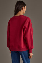 A woman stands with her back to the camera, wearing the Panache Apparel Collection Maroon & Gold Game Day Sweatshirt and blue jeans against a plain brown background. She has long dark hair and is accessorized with hoop earrings.