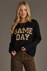 A woman with long blonde hair wears the Panache Apparel Collection Black & Tan Game Day Lightweight Sweater and brown leopard print pants, standing against a neutral backdrop.